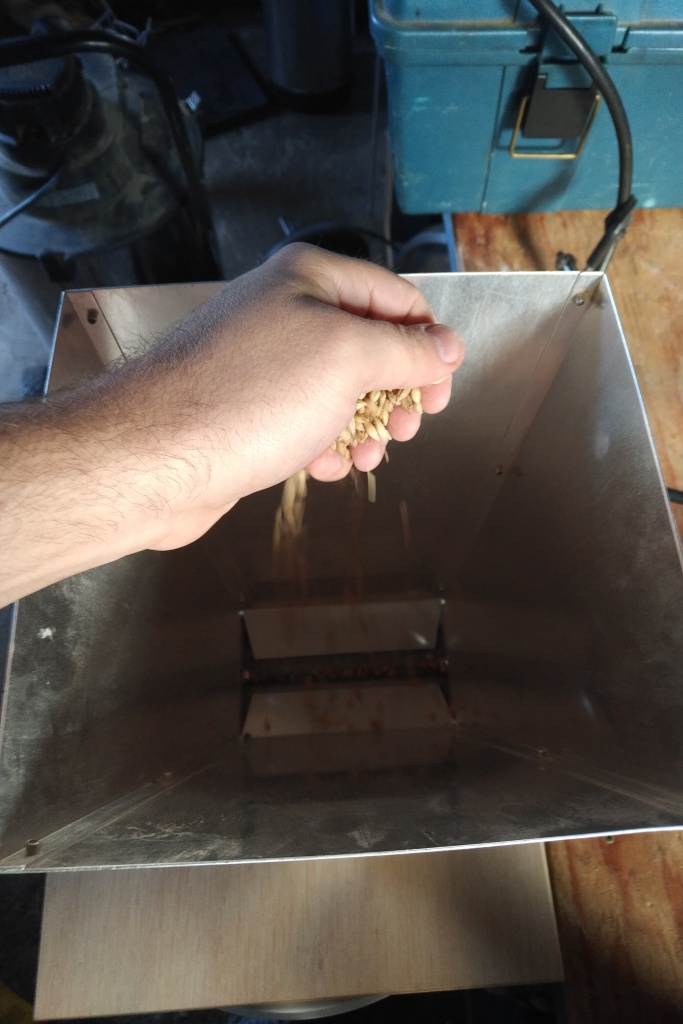 A hand dropping grain into a mill.